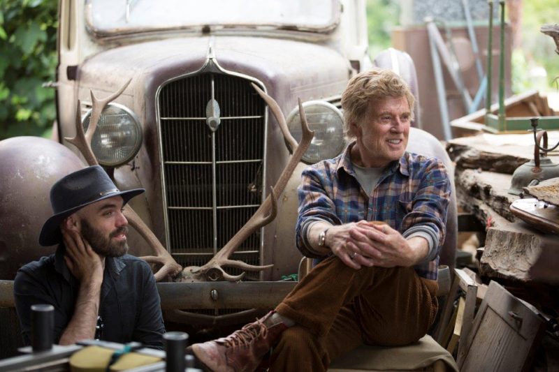 Co-Writer and Director David Lowery (left) and Robert Redford asMr. Meacham (right) talk behind the scenes while shooting on location in New Zealand.