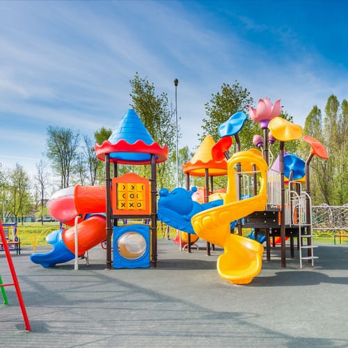 An expansive school playground with two sets of equipment in bright colors. The surface is nice and smooth.